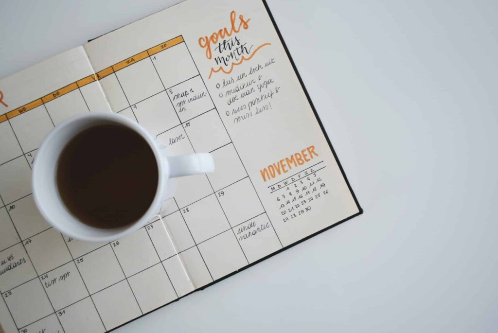 A planner with a cup of coffee showing someone how to set goals